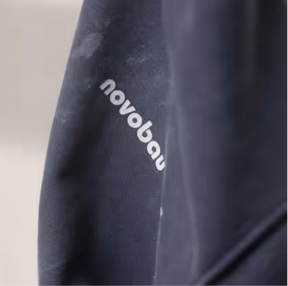 Nahaufnahme eines dunkelblauen Kleidungsstücks mit dem weißen Schriftzug 'novobau'.